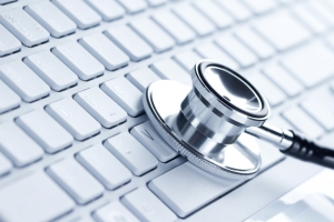 Silver stethoscope lying down on an laptop, toned blue